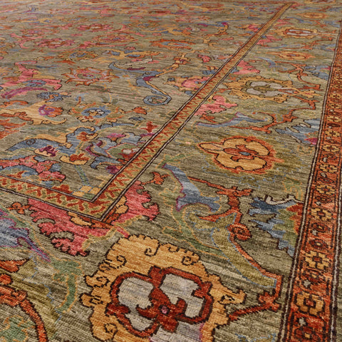 A close-up view of a traditional oriental-style area rug with an intricate floral pattern in muted tones of green, blush pink, golden wheat, peiwinkle blue and touches of burnt Sienna.