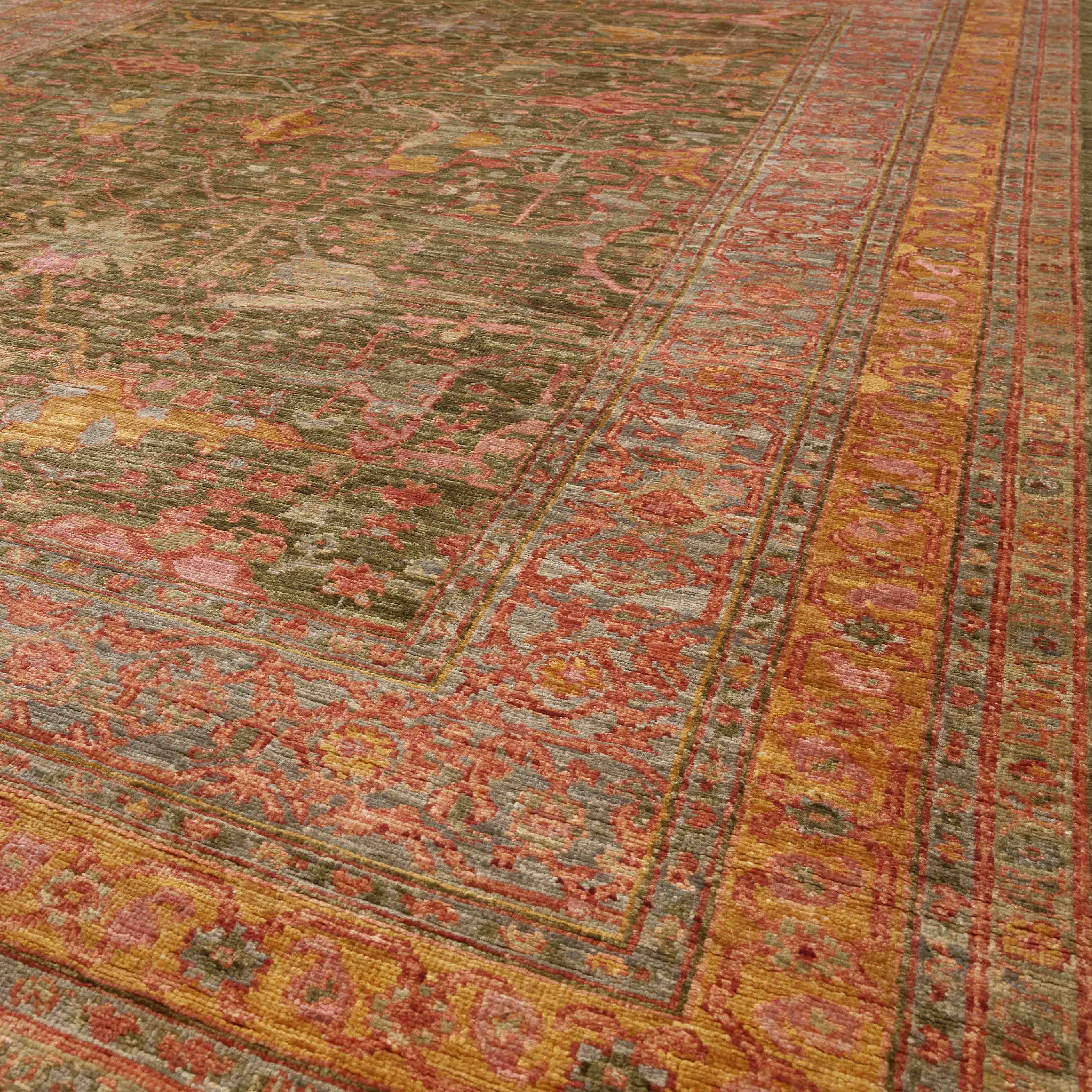 A close-up view of a traditional oriental-style area rug with a distressed pattern, featuring a dark olive-green centre field and a wide tangerine border with rose pink and crushed raspberry details.