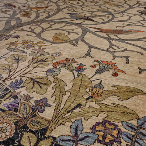 A close-up of a woven area rug featuring a detailed botanical and avian pattern with beige, olive green, blue, orange, and purple tones.
