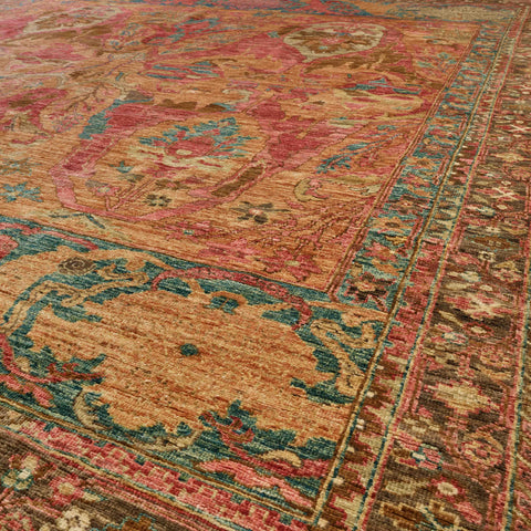 A close-up view of a traditional oriental rug with a faded vintage pattern in warm spice colours with old rose, crushed raspberry, and touches of teal.