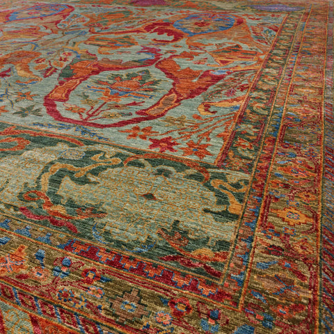 A close-up view of a traditional oriental-style area rug with a colour palette of greens, papaya, blue, crimson, gold and mocha.