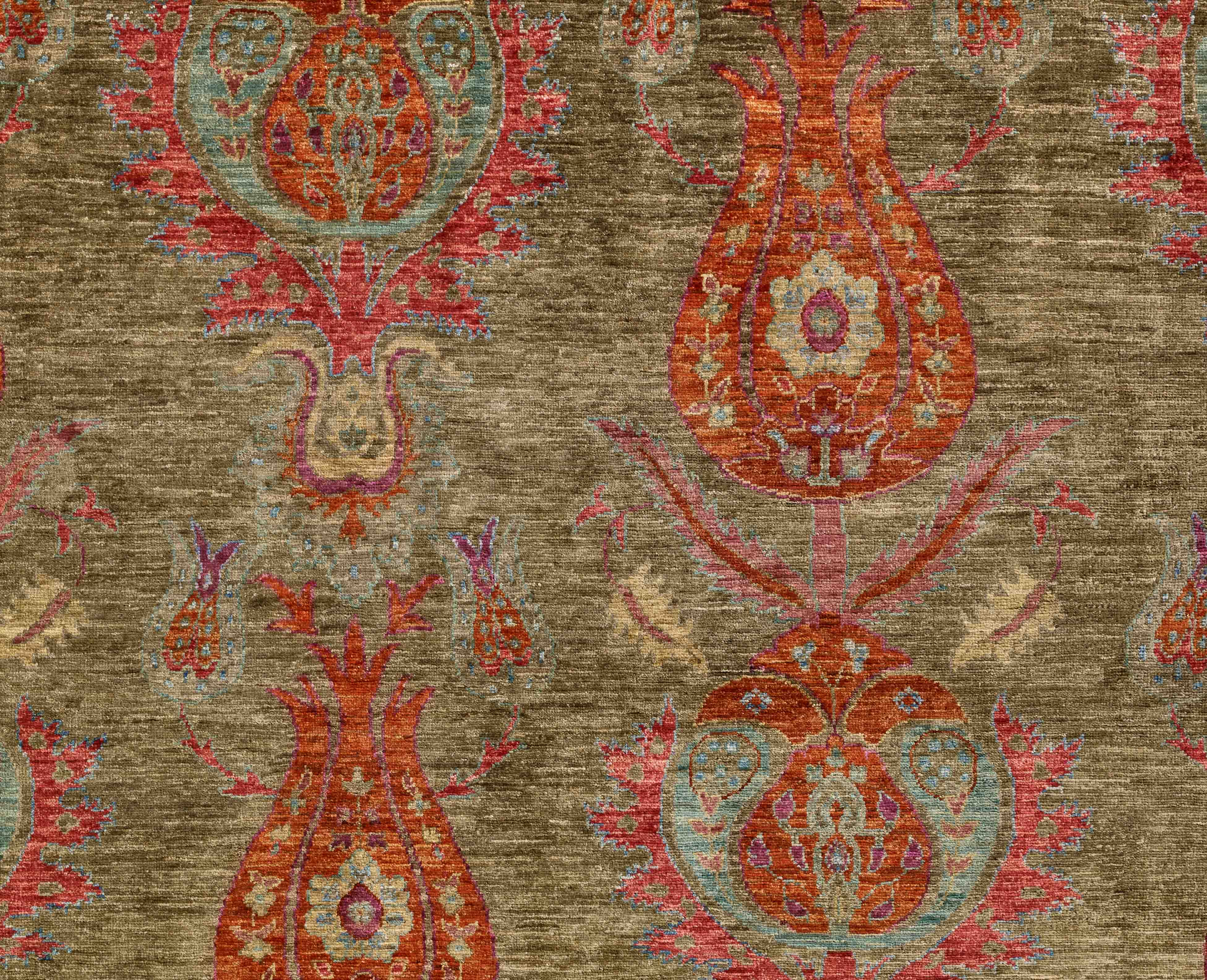 A close-up of a textured  rug featuring an ornate tulip design in olive green, burnt orange, heather and sand colourings.