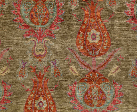 A close-up of a textured  rug featuring an ornate tulip design in olive green, burnt orange, heather and sand colourings.