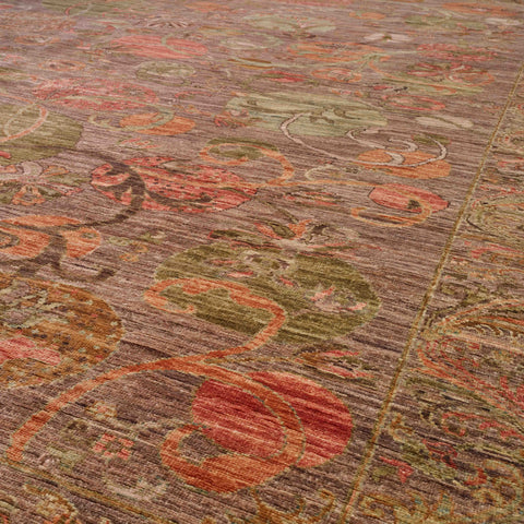 A close-up view of an ornate area rug with a distressed traditional pattern in muted tones of brown, rust red, sage green, and beige.