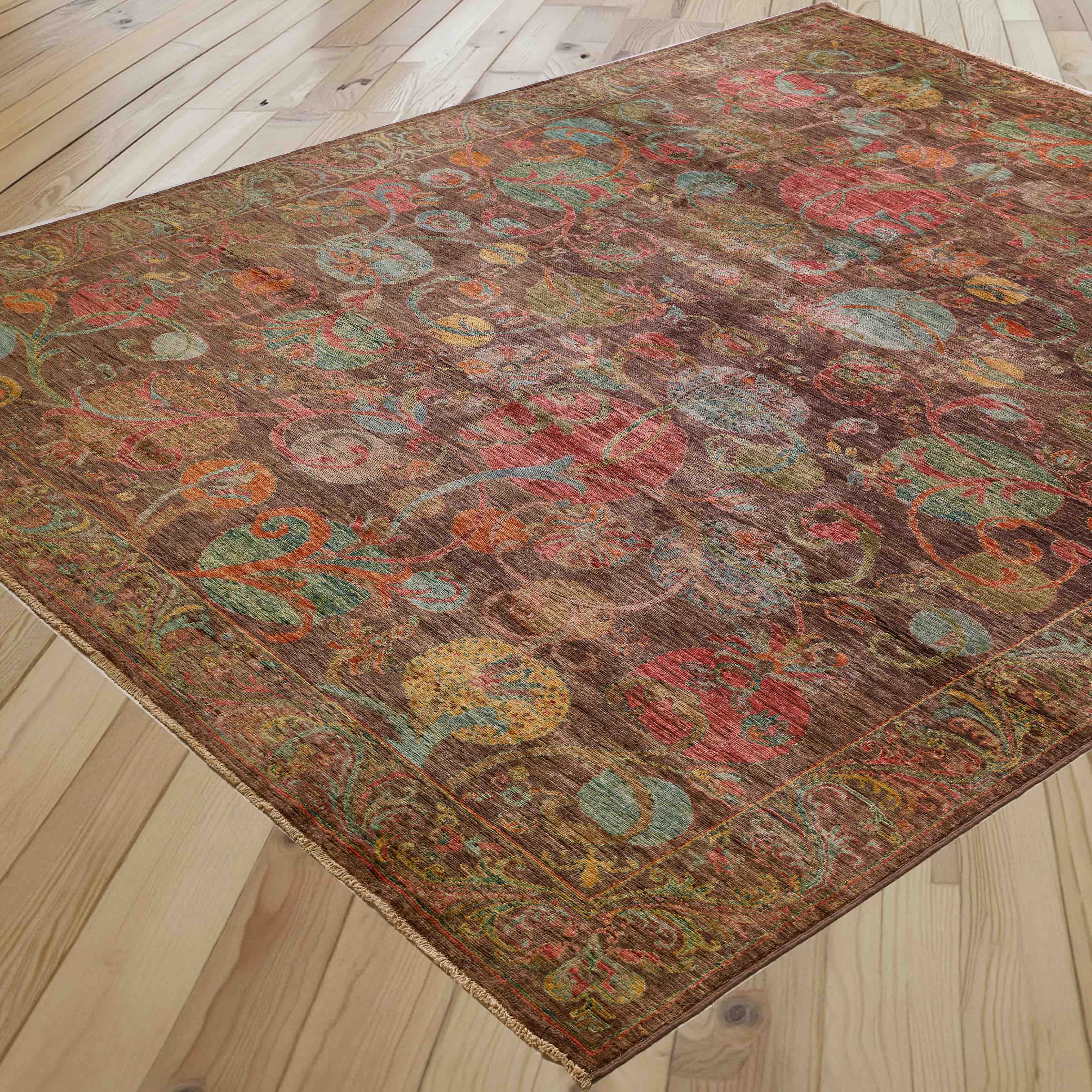 A rectangular vintage-style area rug with an intricate multicolour floral and medallion pattern, shown laid out on a light-colored wooden plank floor.