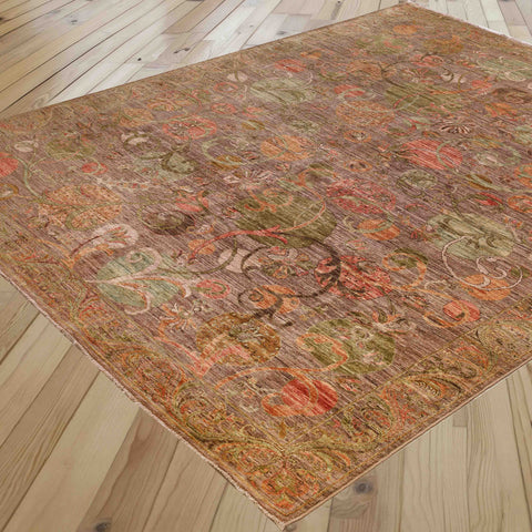 An area rug with an intricate, distressed traditional pattern in earthy tones of brown, rust orange, sage green, and beige, shown laid out on a light wood plank floor.