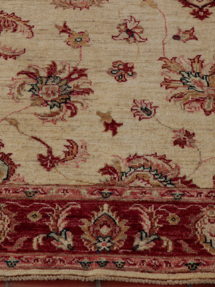 A hand knotted Afghan Ziegler runner with a cream background and soft red border.