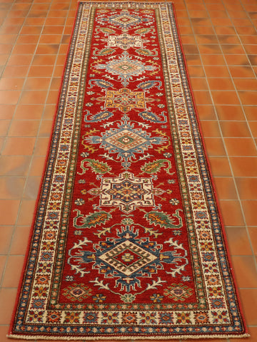 Strong red ground in the central section with 6 decorated motifs, laid out symmetrically through the length of the runner.  There are 3 main borders one being cream that is slightly broader than the other two.  All of the decoration has a colour palette of cream, blue, green, and yellow.  These vary in shade. The decorative featues are all based on stylized flora and fauna. 