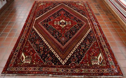 Autumnal tones have been used in this rug.  A large lozenge covers all of the central section with bands of colour and decoration forming the shape.  There is an array of decorative features, motifs and stylized florals.  The colours used are many, reds, browns, blues, greens, creams, yellows and oranges. 